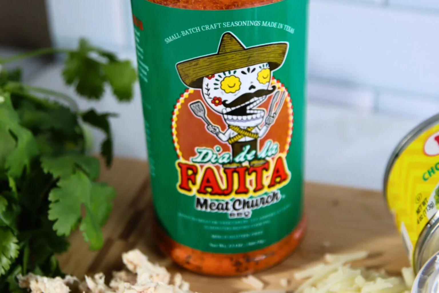 Meat Church Dia de la Fajita seasoning beside cilantro, shredded chicken, and cheese.