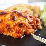 Lasagna on black plate with salad and Bread
