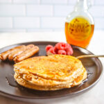 Protein pancakes on black plate with sausage and raspberries